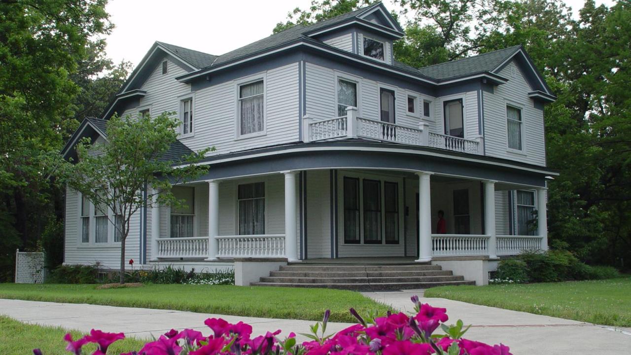 Exterior image of the front of the historic house two stories painted gray with a wrap around porch