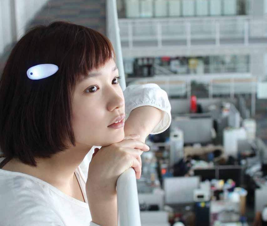 A young girl in profile looks off into the distance. Her plastic hairclip is opaque and appears to be glowing