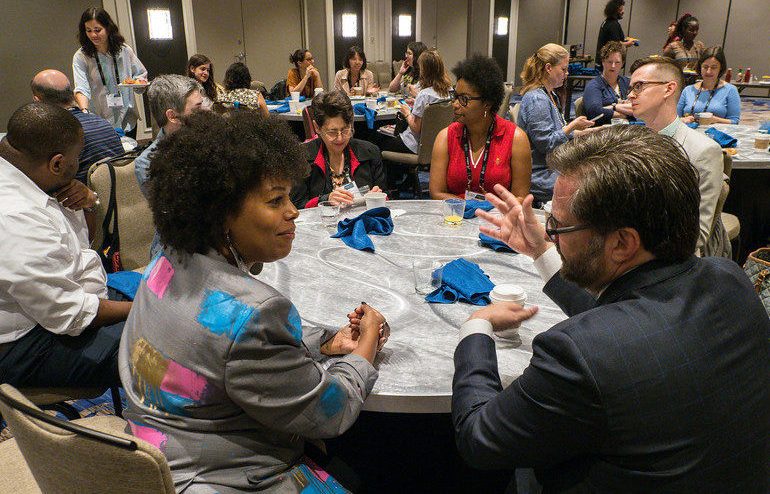 Scholars and guests sitting at tables and networking at the Annual Meeting Scholarship Breakfast.