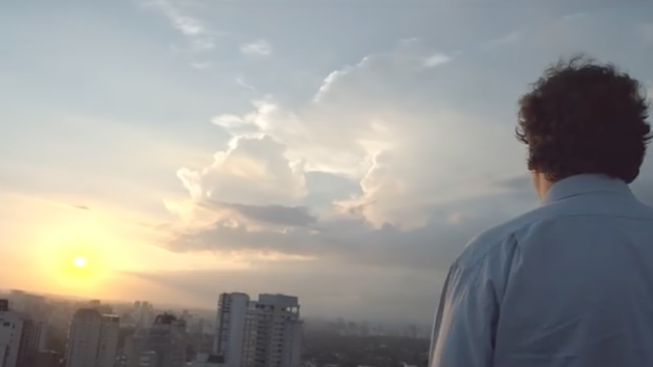 Image of a man staring at a sunset sky with clouds