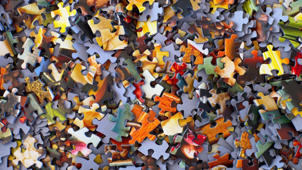 Closeup image of hundreds of puzzle pieces thrown on top of one another some right side up some upside down.