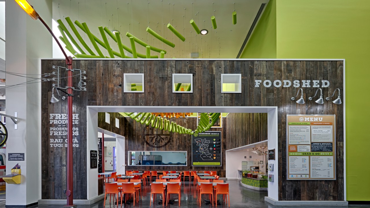 The FoodShed café has wood walls and brightly colored seating and sculptures, and advertises "fresh produce."