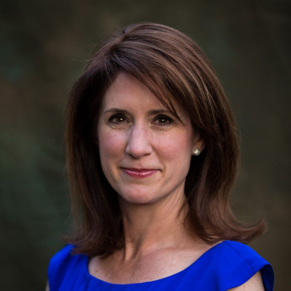 Image of a white woman, Victoria Ramirez, with shoulder length dark brown hair wearing a bright blue top and smiling at the camera. 