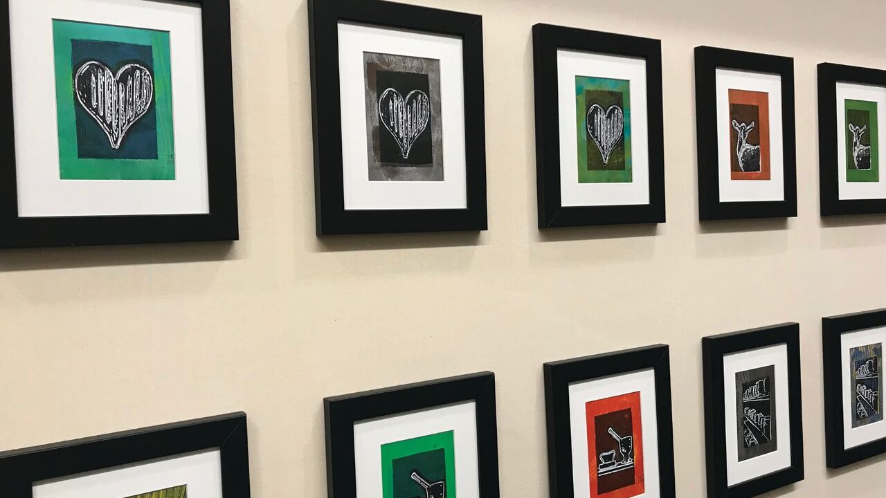 A row of framed artwork hung parallel on a wall.