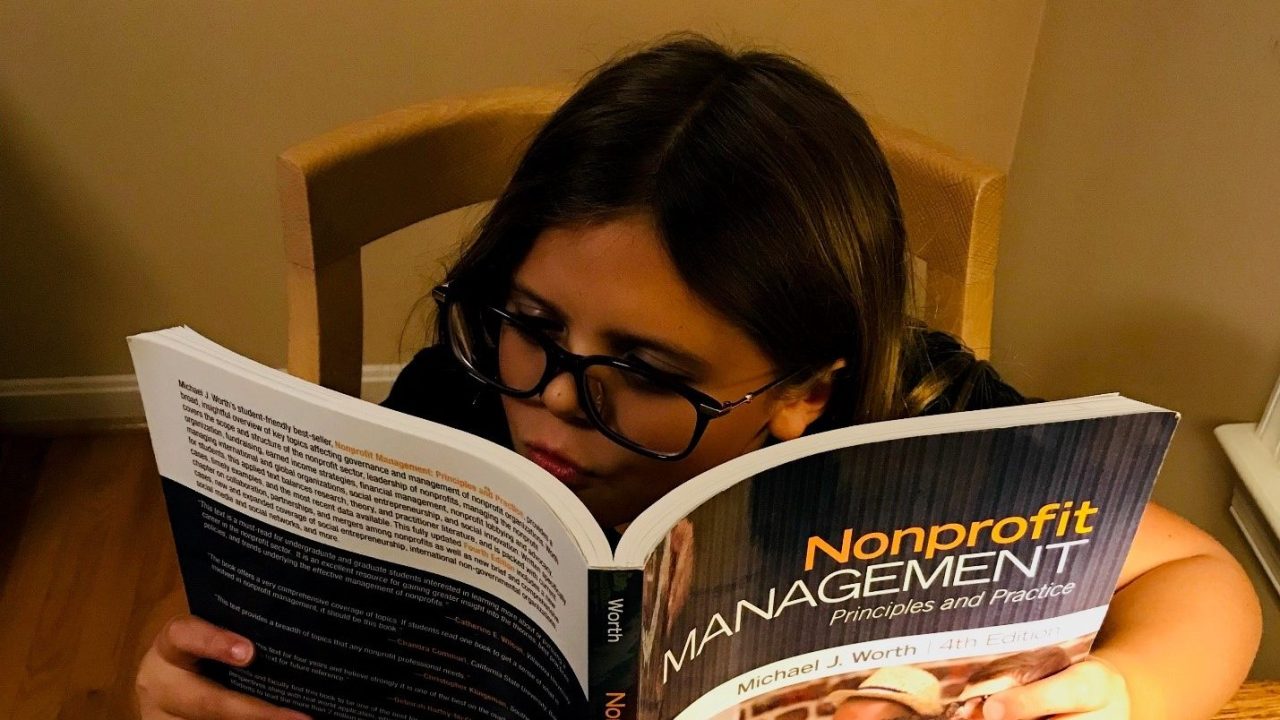 A child sits reading a book called "Nonprofit Management."