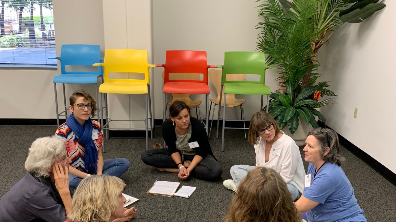 A group of people sitting on the floor in a circle having a discussion