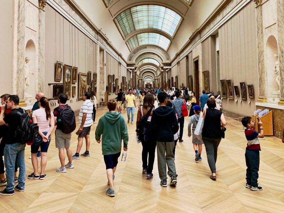 A group of visitors of various ages and ethnicities in a museum hallway