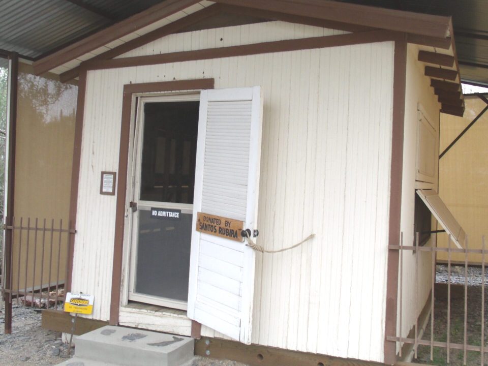 A small one-room cabin displayed with a historical placard