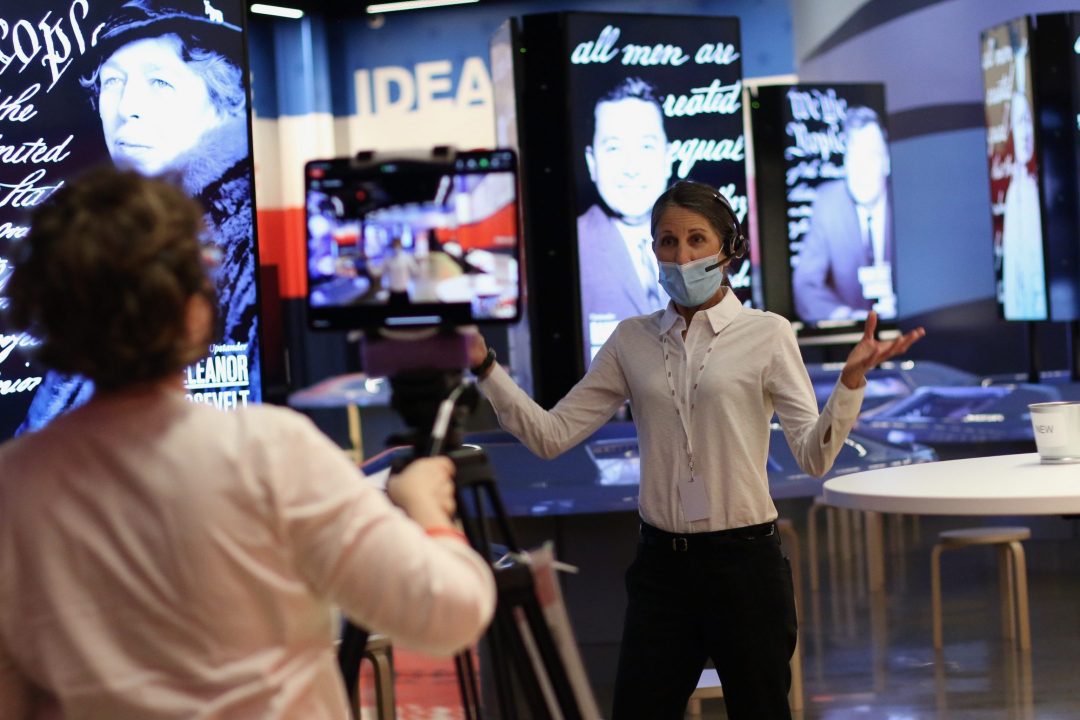 An educator speaking to a camera inside of a museum