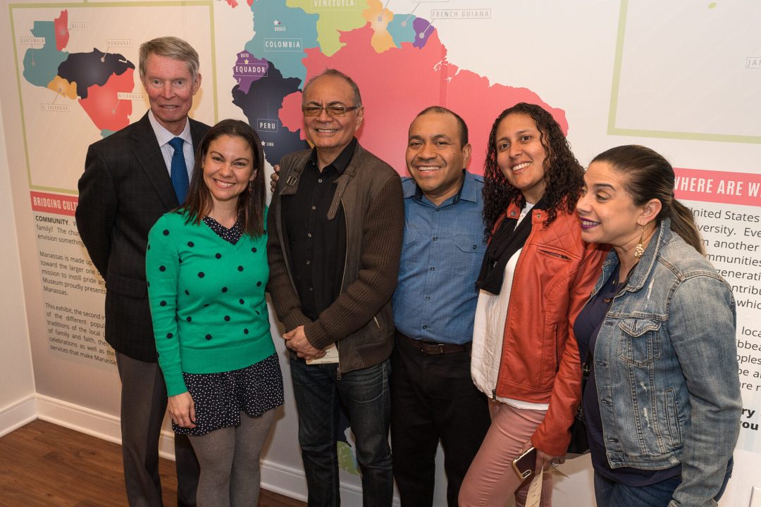 A group of people posed in front of a map inside a museum exhibition