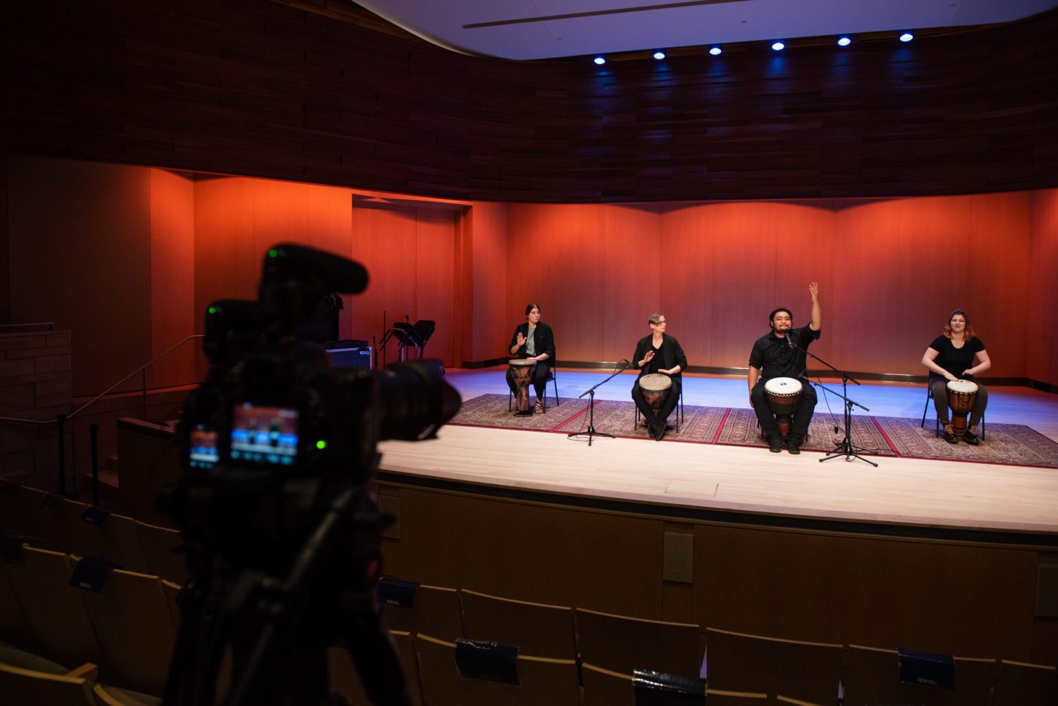 A group of people playing drums in front of microphones on a stage