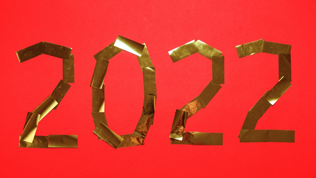 2022 spelled out in gold confetti on a pink background