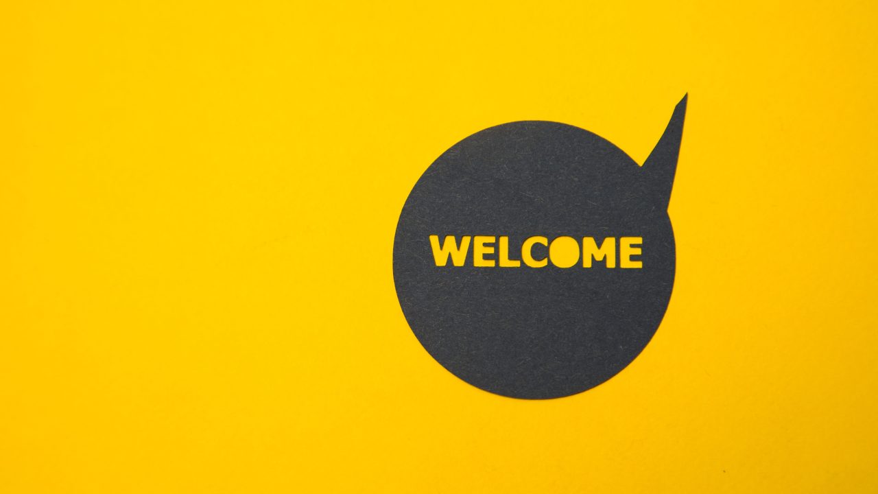 A black speech bubble reading "welcome" on a yellow background