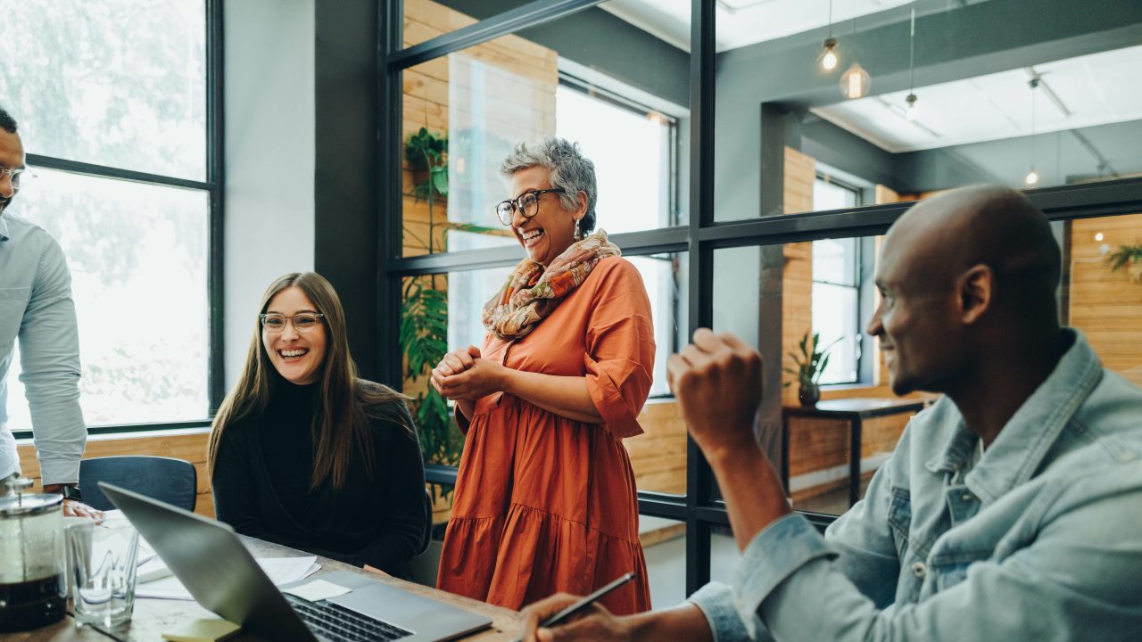 A group of people laughing and smiling in a business meeting