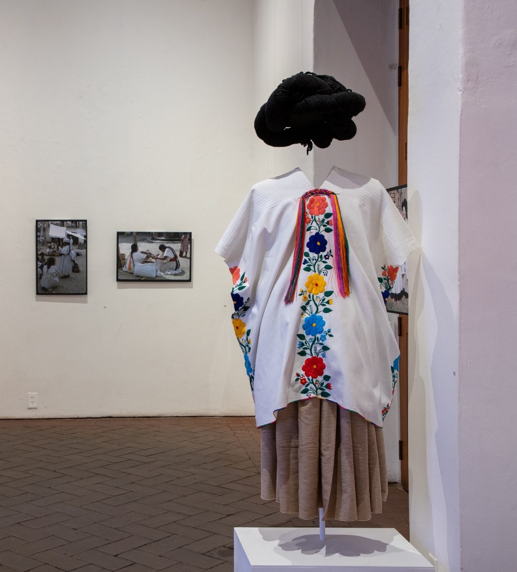 The back of the mannequin with the embroidered shirt and skirt along with a black hat. 