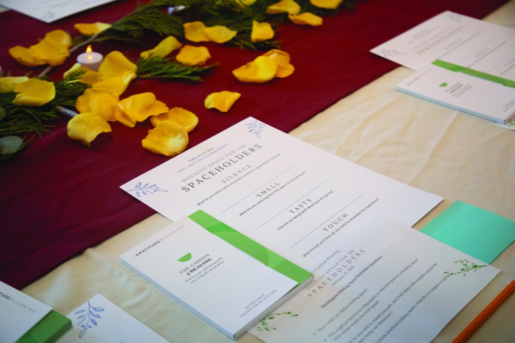 Table settings from an event on a black tablecloth with yellow flower petals sprinkled around.