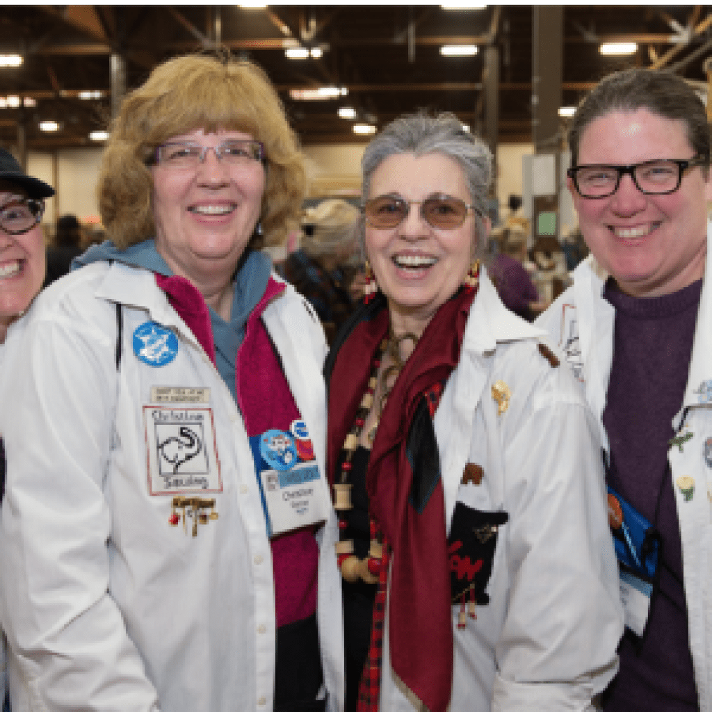 A group of four women each wearing a white lab coat smile at the camera. 