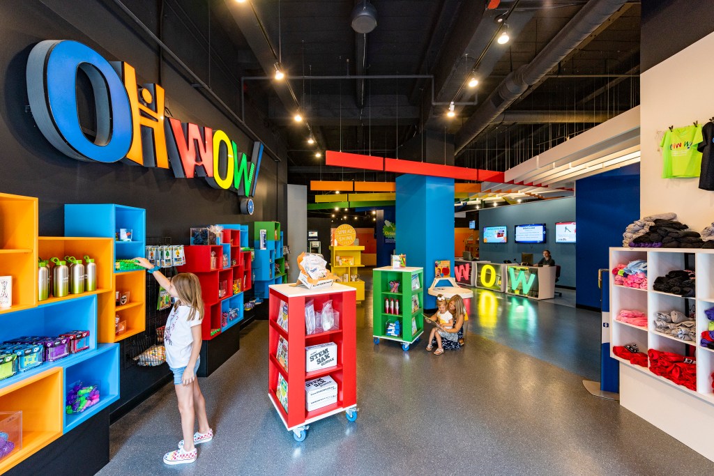 A store with colorful shelving and a neon sign reading "Oh wow!"