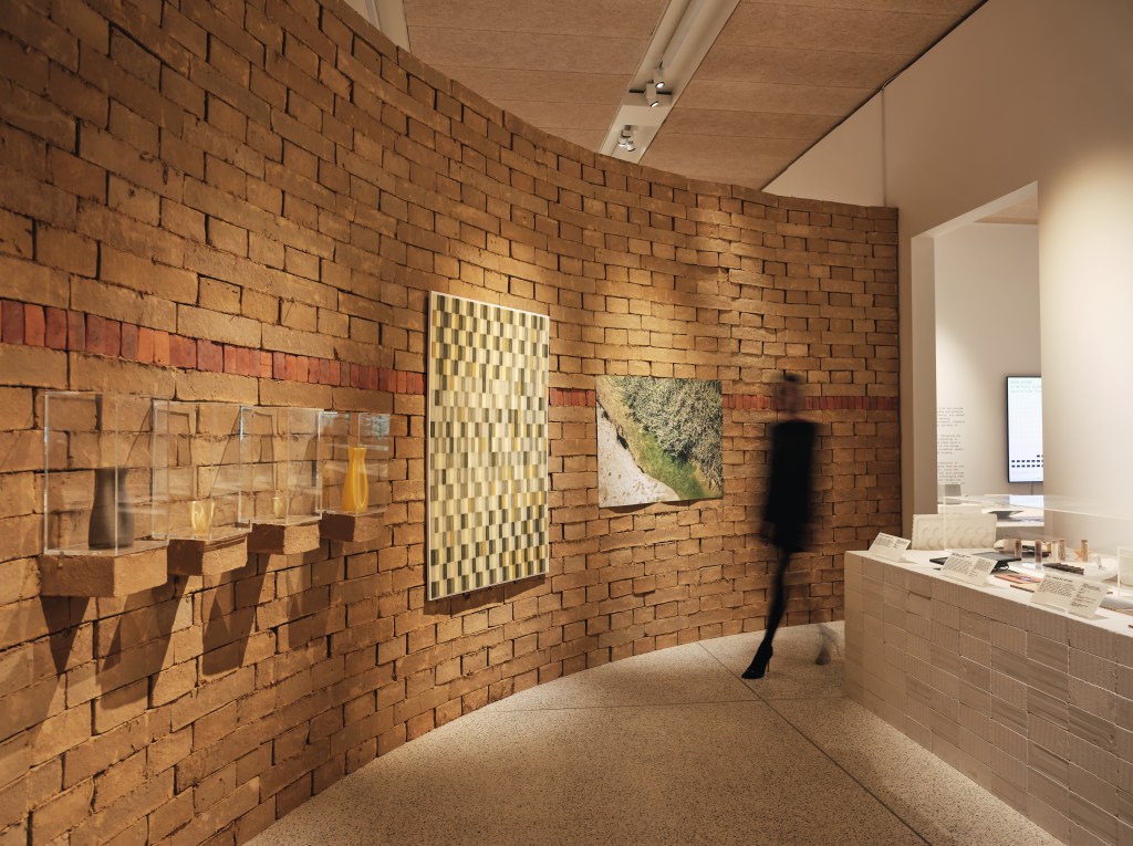 An exhibition gallery with objects mounted on a brick wall