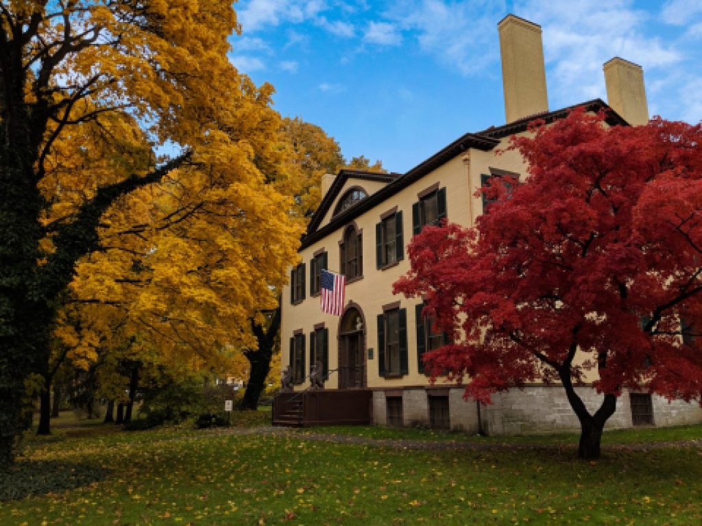 An exterior shot of the State Prison with autumn leaves on several trees.