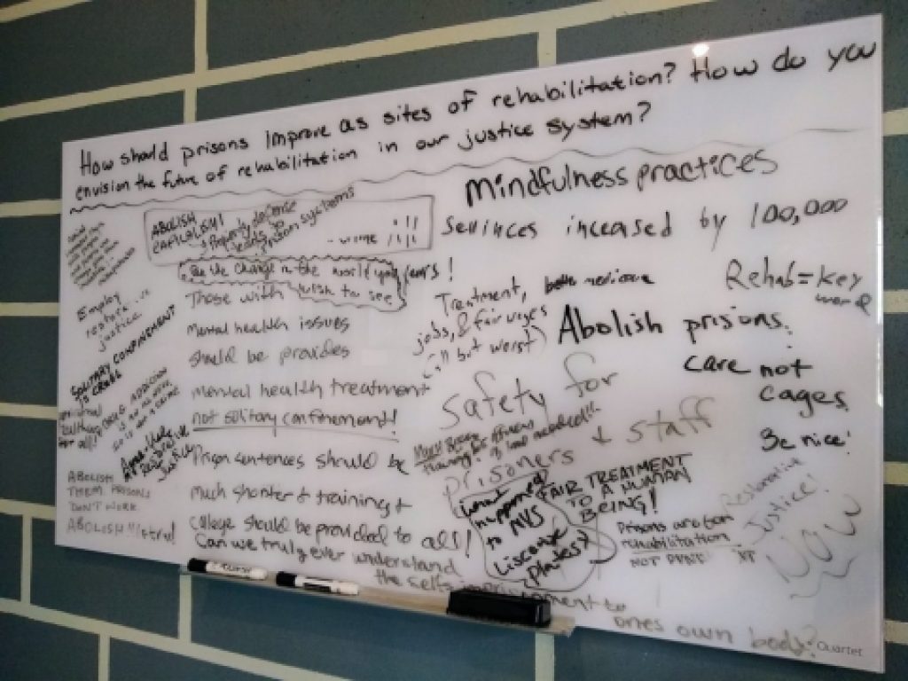 Handwritten notes on a whiteboard hung on a green tiled wall.