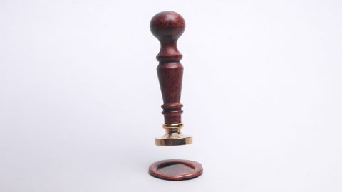 A wooden stamp hovering over a wax seal