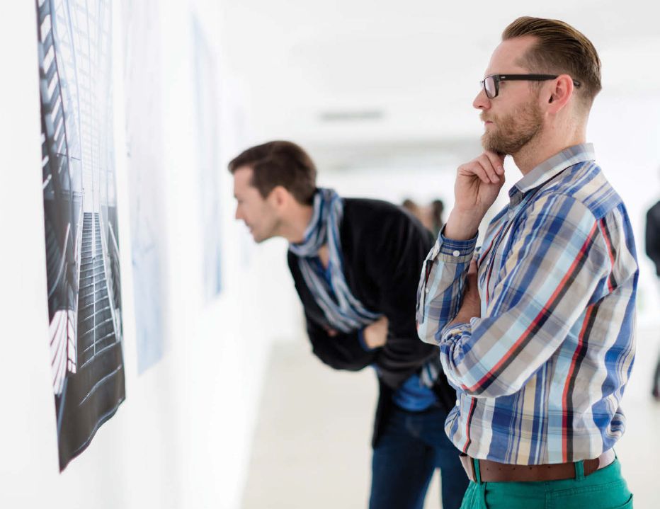 Image of two young white men looking intently at something on the wall.