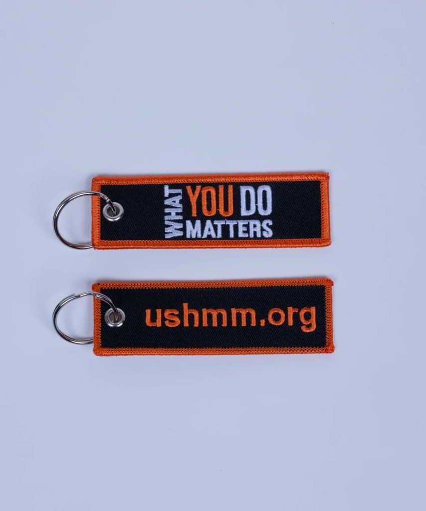 A recto and verso image of a fabric key chain reading "What You Do Matters" on one side and "ushmm.org" on the other side.