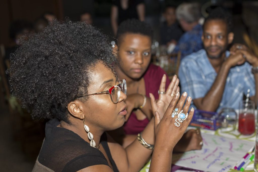 Several individuals sit at a table and share in a discussion