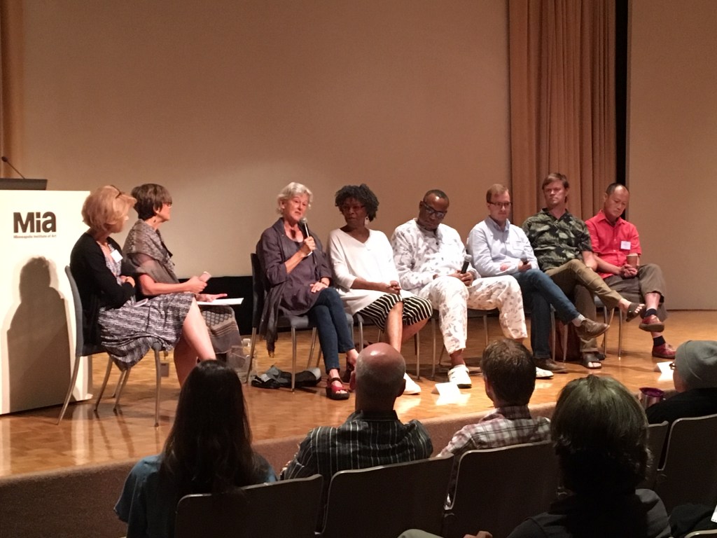 A panel discussion on a stage with a podium bearing the Minneapolis Institute of Art logo