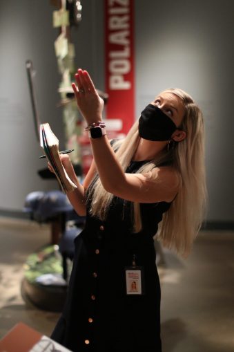 An educator inside a gallery pointing to something on a wall