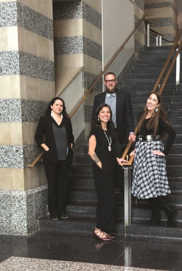 Four adults stand on a stairwell in the museum smiling at the camera.